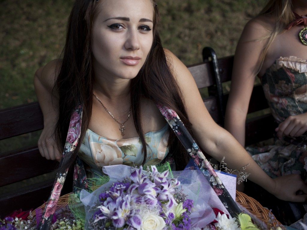 Girls in old time dresses selling flowers in Sevastopol are pictured taking a rest of a bench. Crimea 03.08.2014